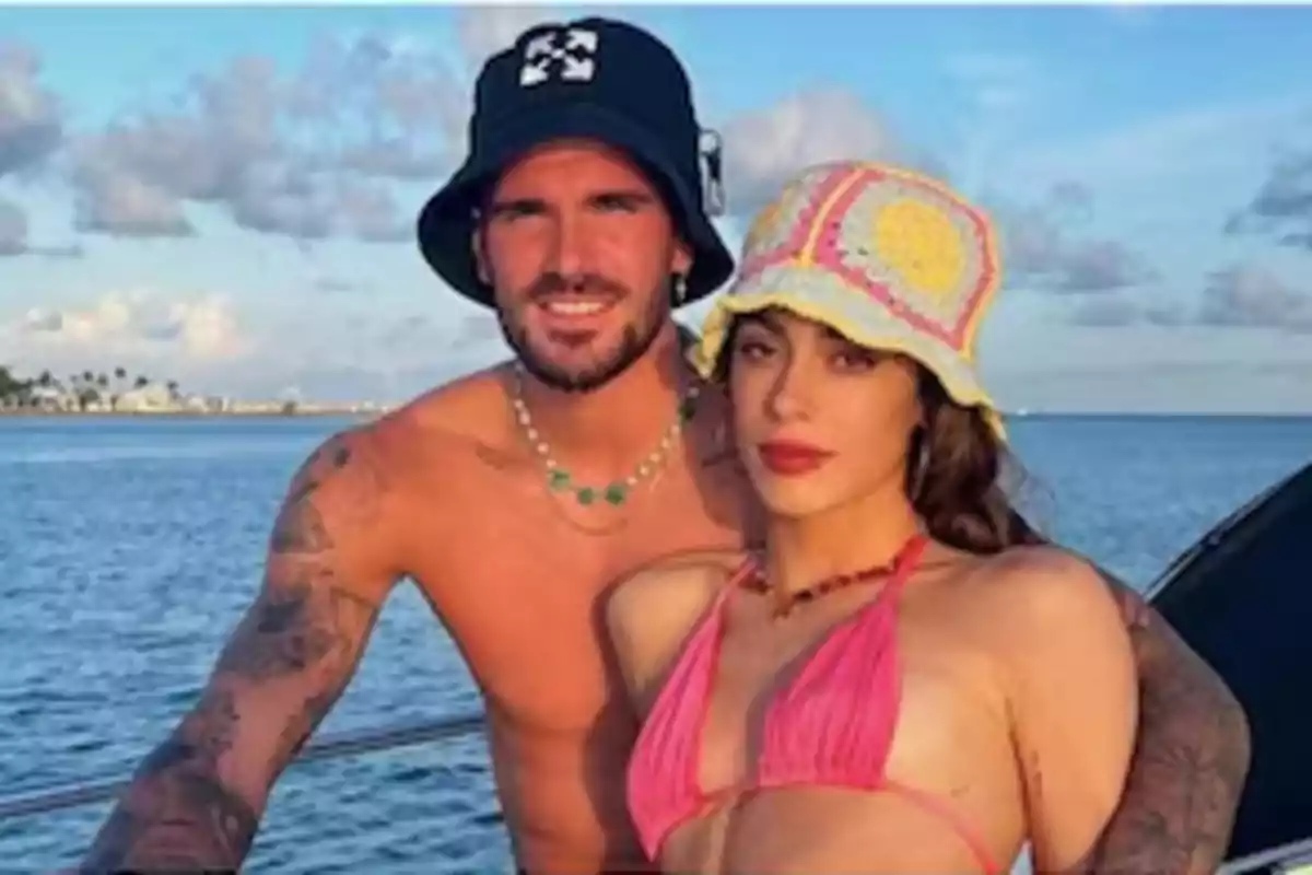 Two people posing on a boat with the sea in the background.