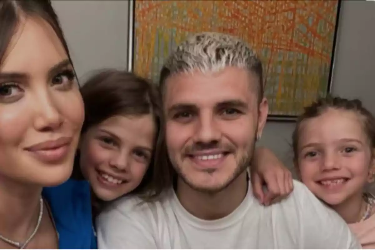 Una mujer, un hombre y dos niñas sonríen mientras posan para una foto frente a un cuadro colorido.