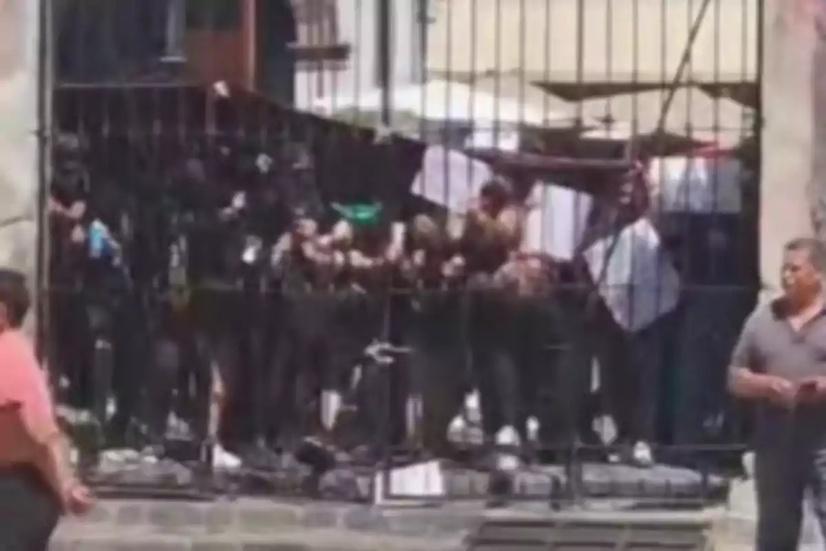 A group of people behind a fence in an urban setting.