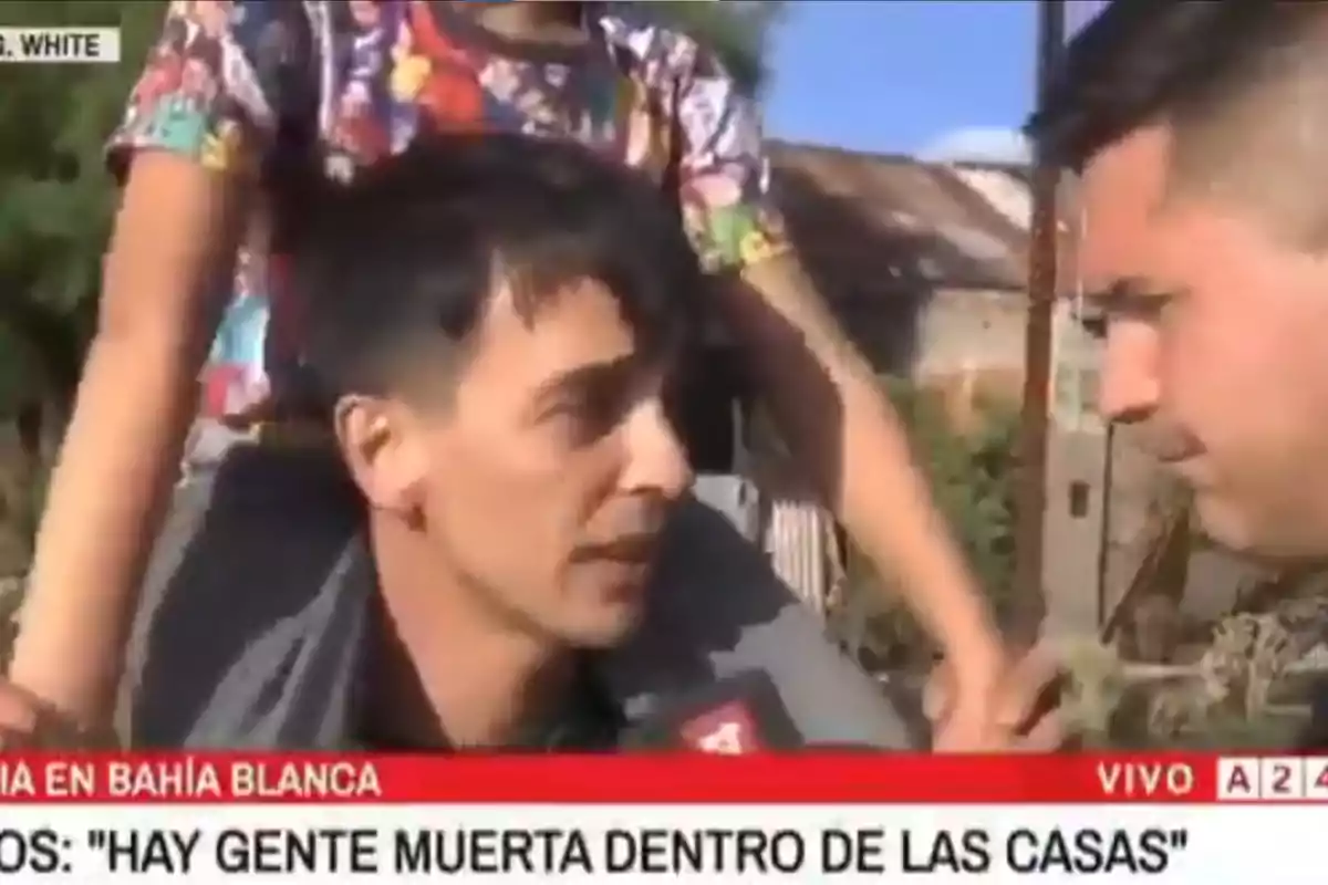 Un reportero entrevista a un hombre en la calle mientras un niño está sobre los hombros del entrevistado.