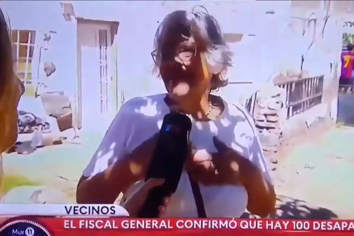 Una persona mayor es entrevistada en la calle por un reportero que sostiene un micrófono, mientras en la parte inferior de la imagen se muestra un texto de noticias.