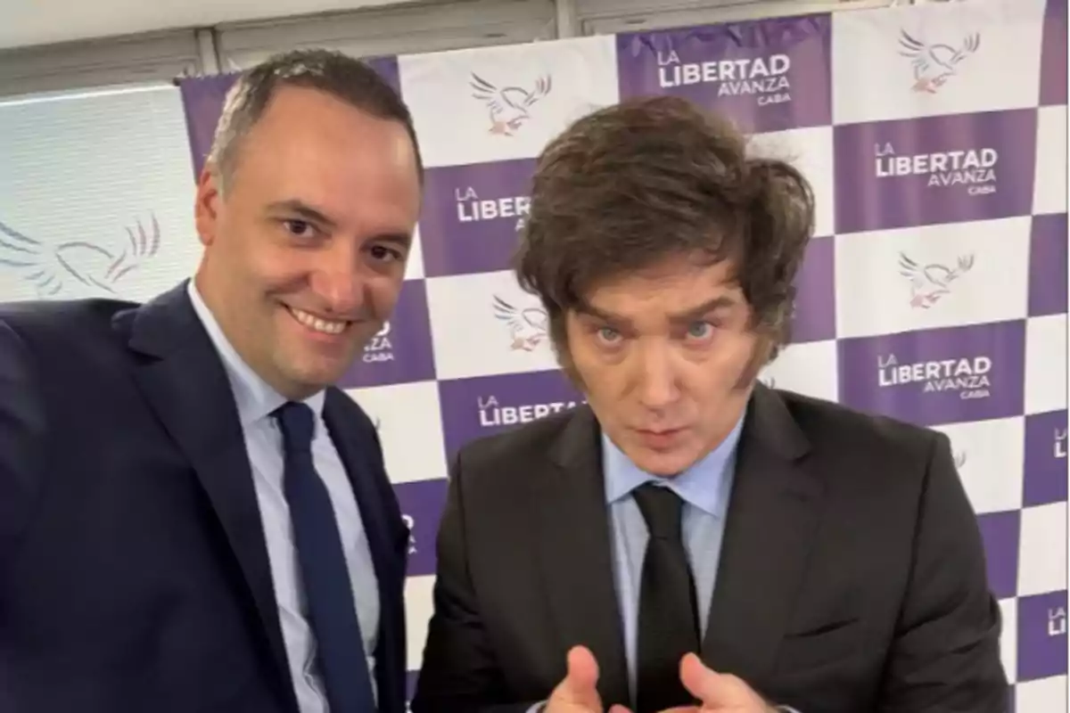 Dos personas posan para una foto frente a un fondo con el logotipo de Dos personas posan para una foto frente a un fondo con el logotipo de