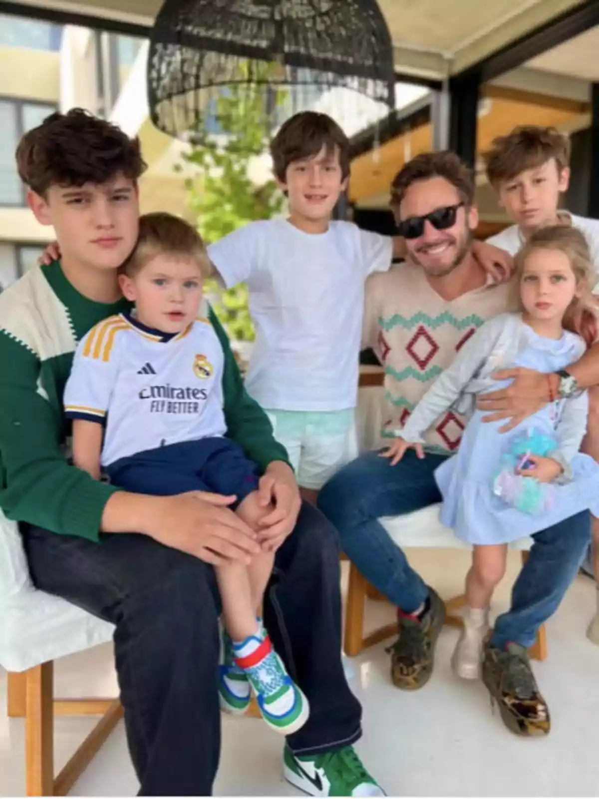 Un grupo de personas, incluyendo adultos y niños, posan juntos en un ambiente interior con decoración moderna. Un grupo de personas, incluyendo adultos y niños, posan juntos en un ambiente interior con decoración moderna.