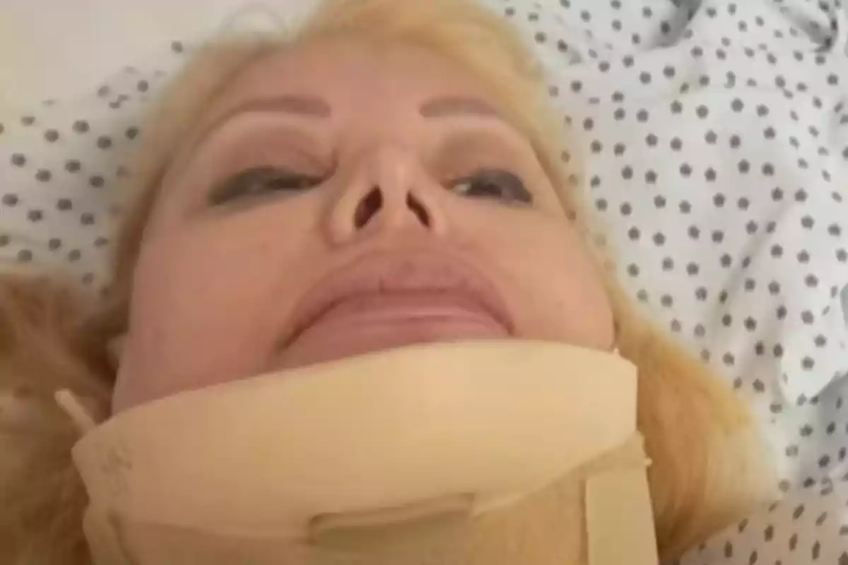 Una persona con collarín acostada en una cama de hospital.