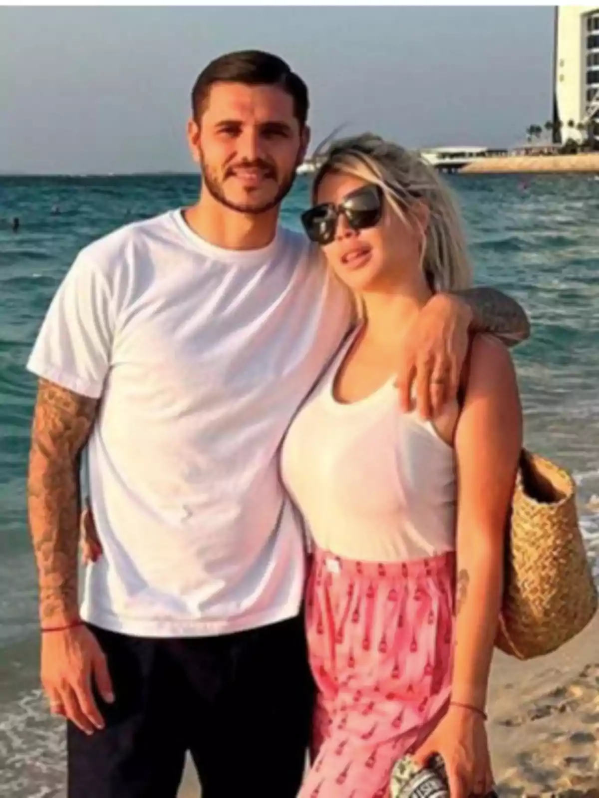 A couple posing on the beach with the sea in the background, both wearing casual clothes and hugging. A couple posing on the beach with the sea in the background, both wearing casual clothes and hugging.