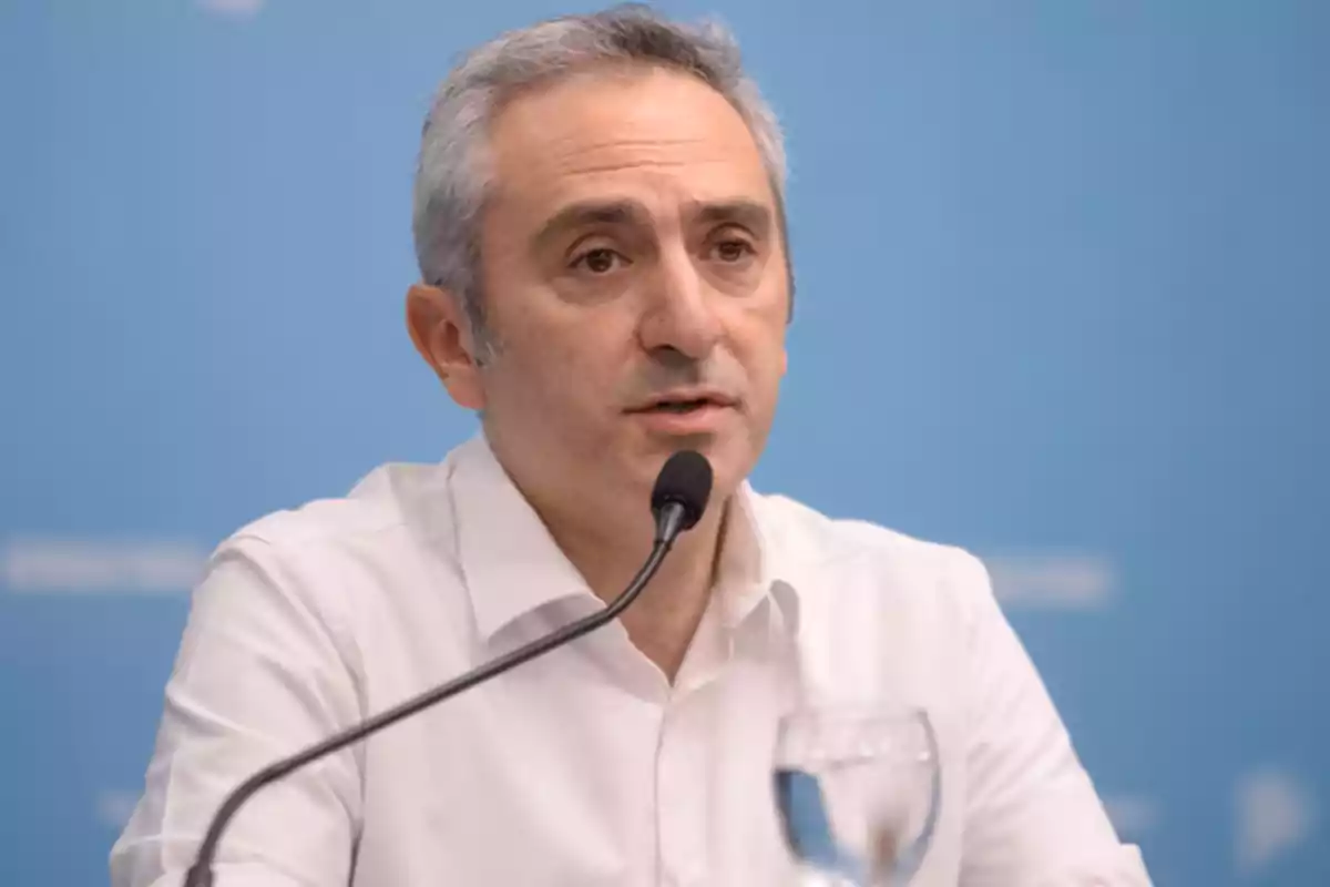 Hombre de cabello canoso hablando en un micrófono con fondo azul. Hombre de cabello canoso hablando en un micrófono con fondo azul.