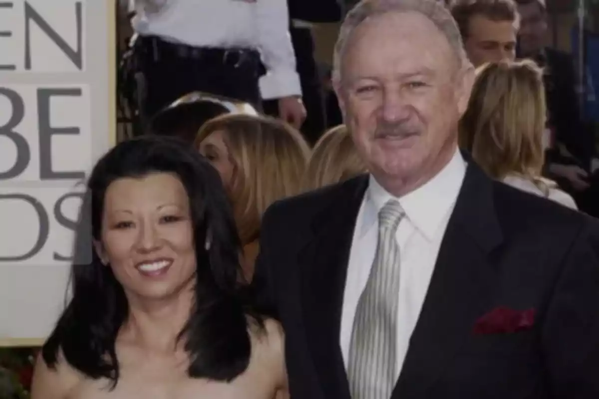 A smiling couple posing at a formal event with a sign in the background.
