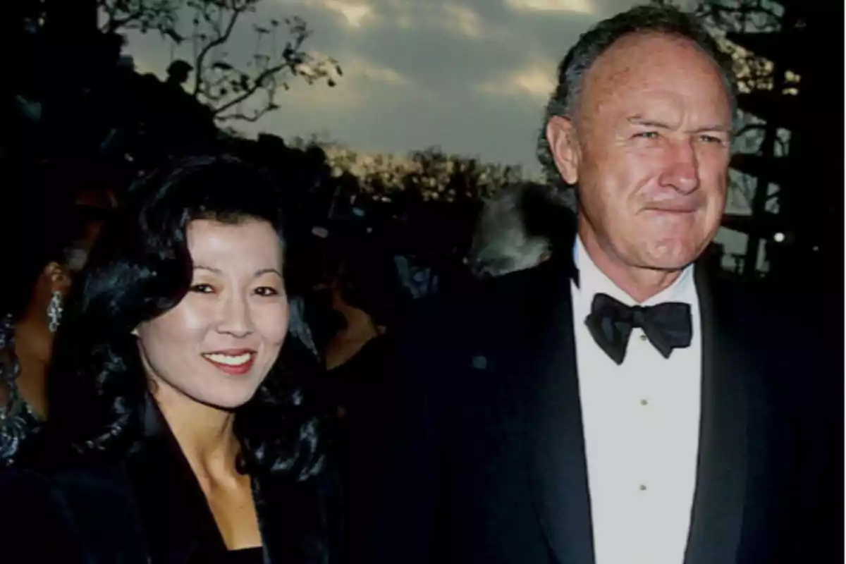 A couple dressed in formal attire smiles while posing for a photo at an outdoor event at sunset. A couple dressed in formal attire smiles while posing for a photo at an outdoor event at sunset.