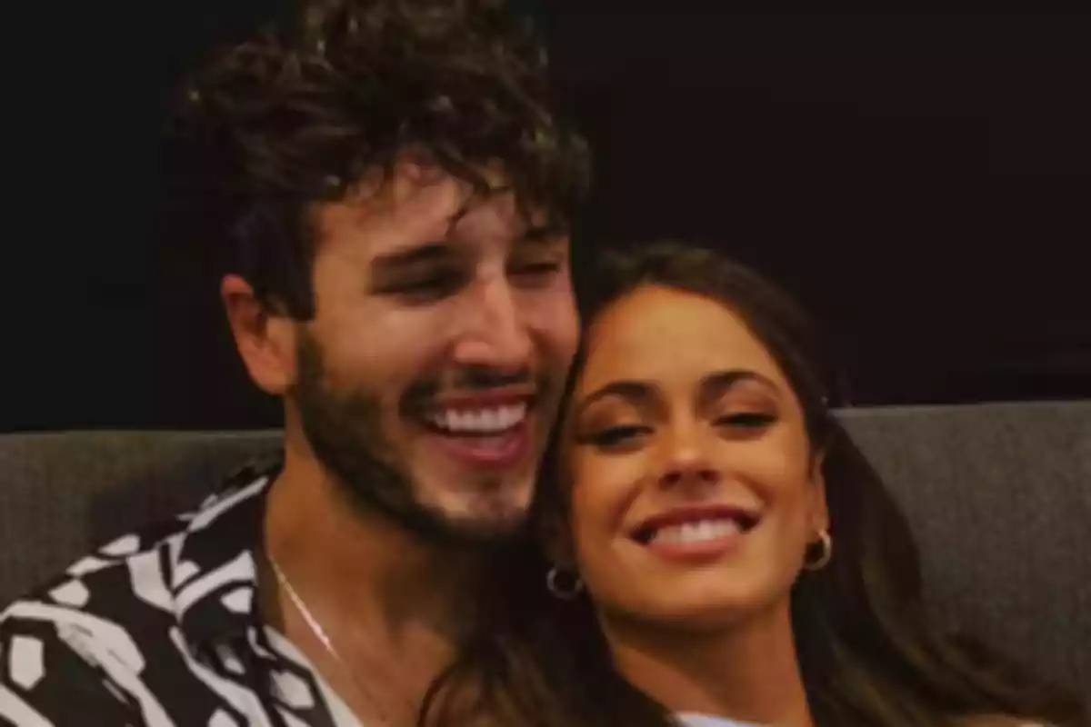 A smiling couple sitting on a sofa.