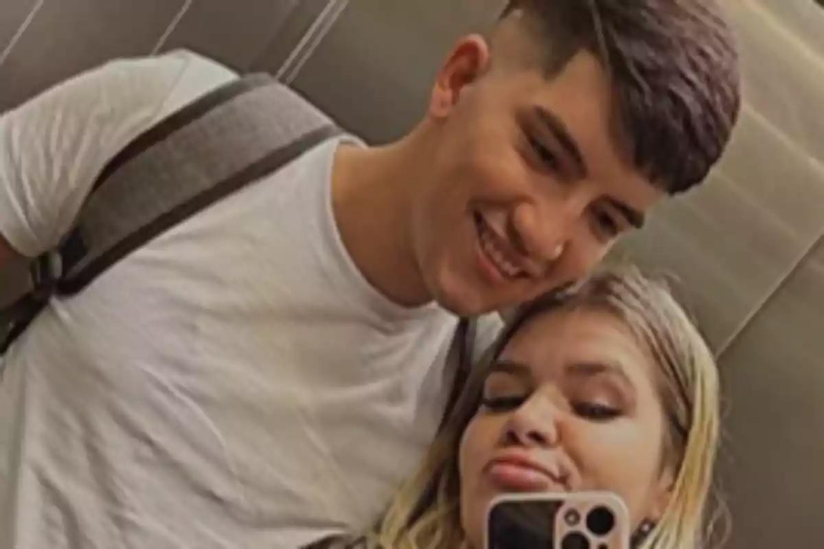 A young couple taking a selfie in an elevator, both smiling and seeming to enjoy the moment.