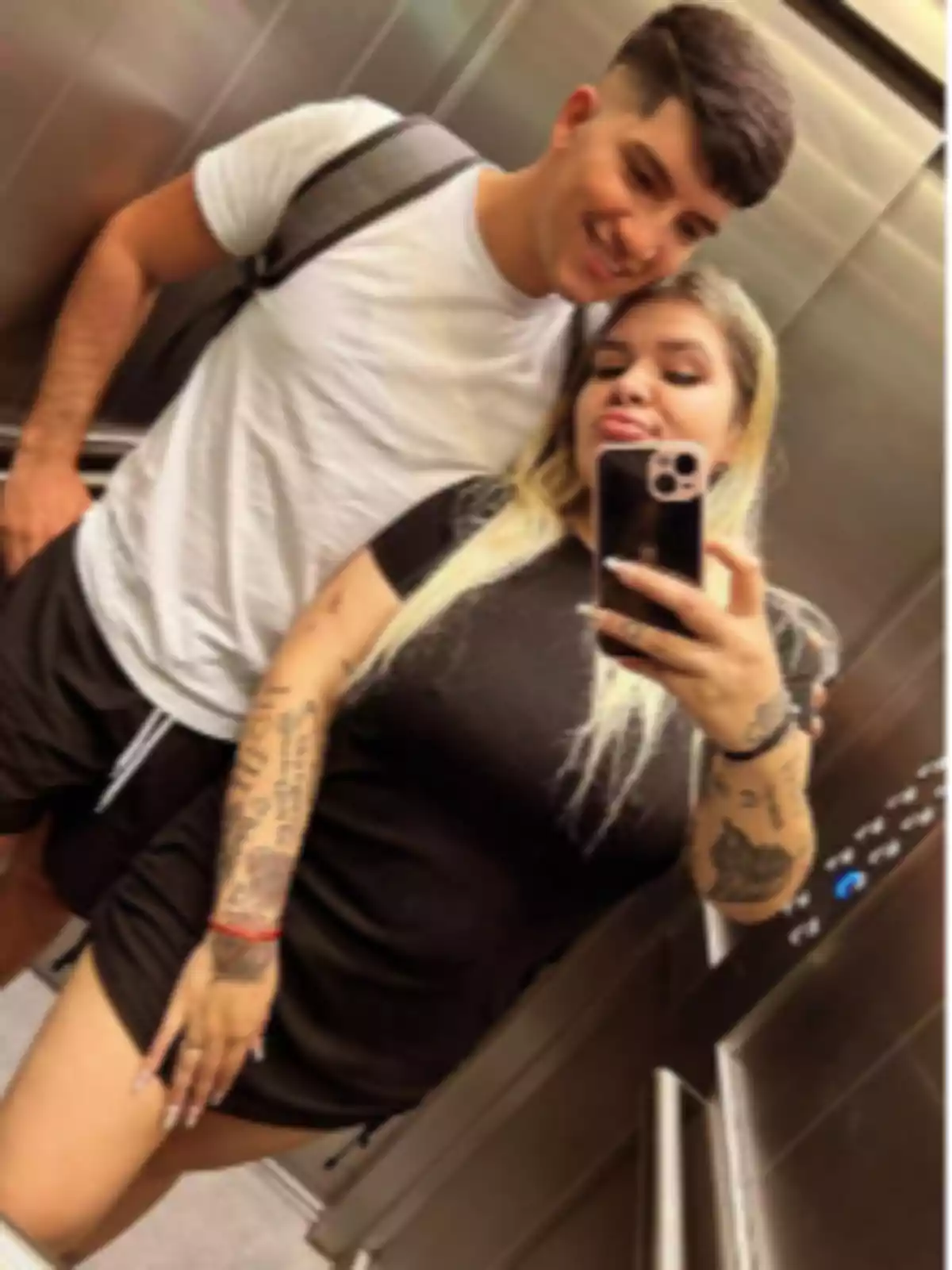 Two people posing for a selfie in an elevator, one with their arm around the other, both wearing casual clothes and smiling at the camera. Two people posing for a selfie in an elevator, one with their arm around the other, both wearing casual clothes and smiling at the camera.