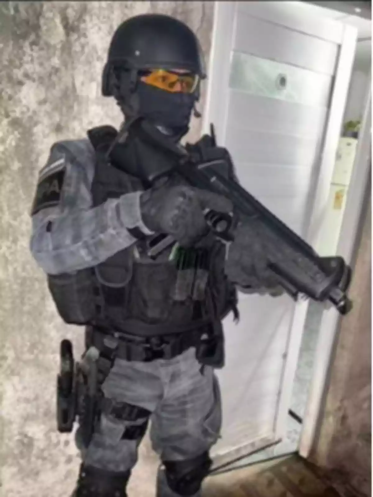 Un agente de seguridad con equipo táctico y un arma en posición de alerta frente a una puerta. Un agente de seguridad con equipo táctico y un arma en posición de alerta frente a una puerta.