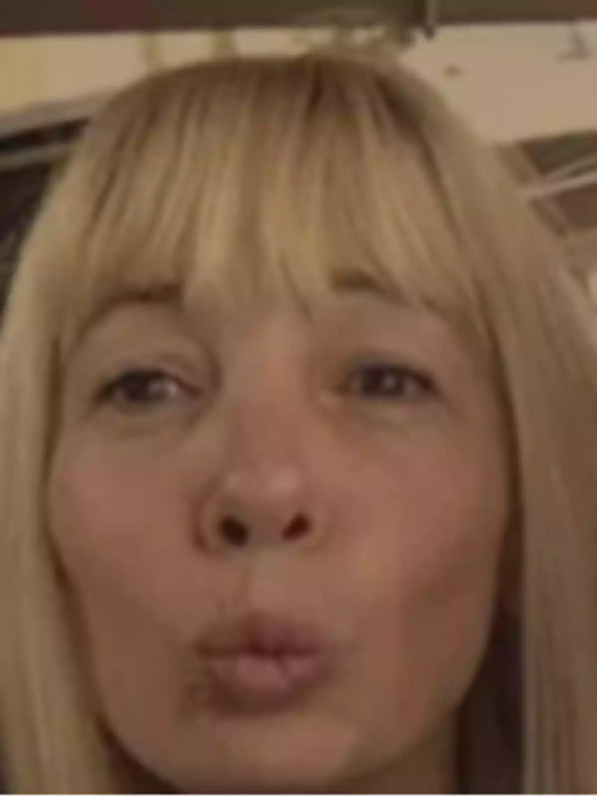 Una persona con cabello rubio y flequillo está haciendo un gesto con los labios fruncidos. Una persona con cabello rubio y flequillo está haciendo un gesto con los labios fruncidos.
