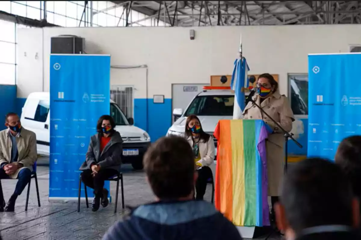 Personas en un evento en un espacio cerrado con banderas y pancartas.