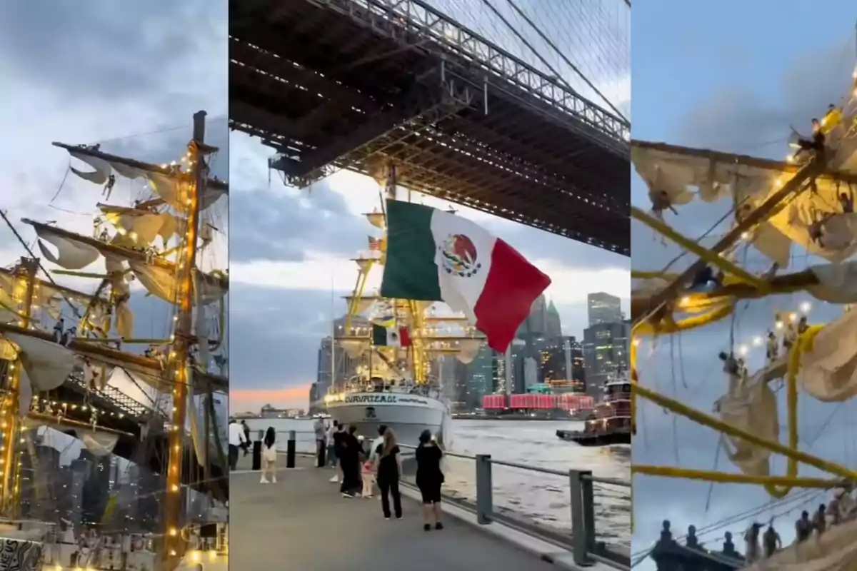A sailboat lit with lights passes under a bridge, waving a large Mexican flag, while people watch from the pier and the city skyline is visible in the background.