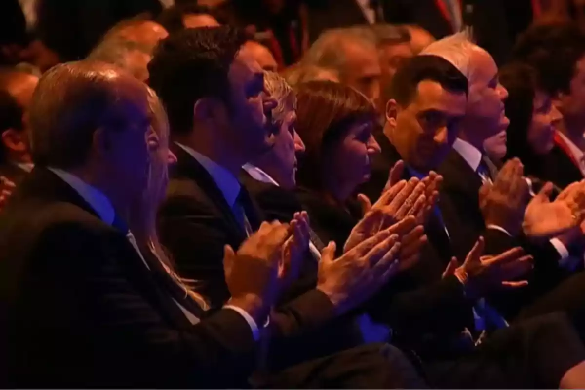 Personas aplaudiendo en un evento formal. Personas aplaudiendo en un evento formal.