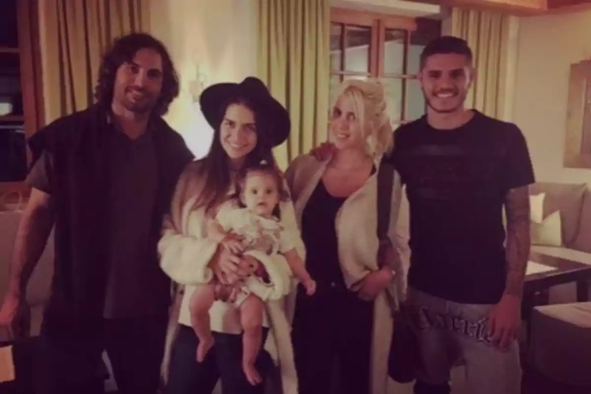 A group of people posing for a photo in a living room, a woman holding a baby while everyone smiles at the camera. A group of people posing for a photo in a living room, a woman holding a baby while everyone smiles at the camera.