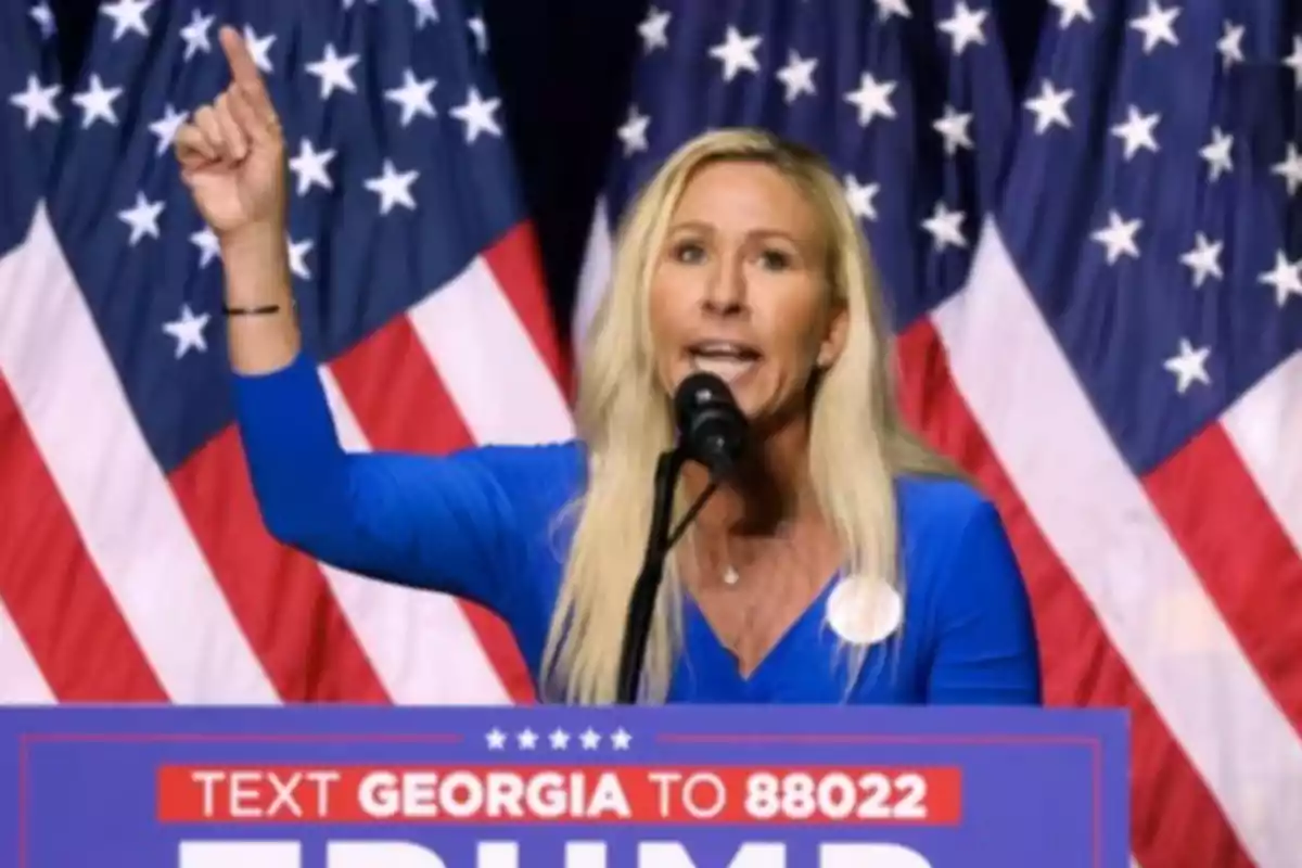 Woman speaking at a rally in front of American flags.