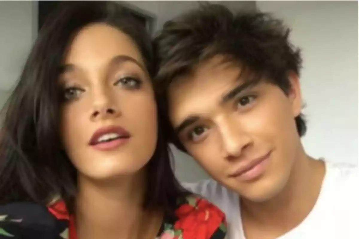 Dos personas posando juntas para una selfie, una mujer con cabello oscuro y un hombre con cabello castaño, ambos mirando a la cámara.
