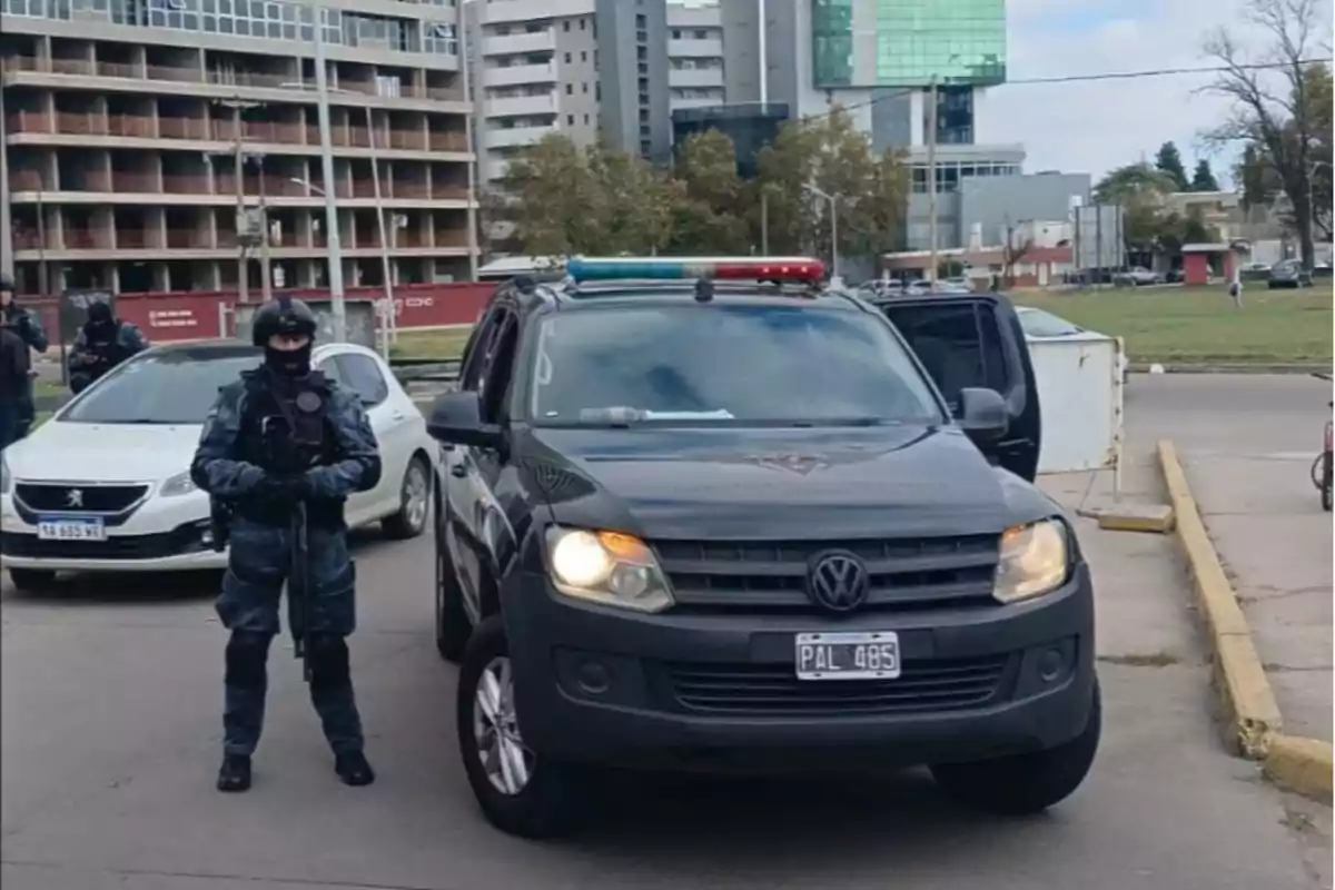 Heavily armed police officer standing next to a black Volkswagen van with its lights on in an urban street Heavily armed police officer standing next to a black Volkswagen van with its lights on in an urban street