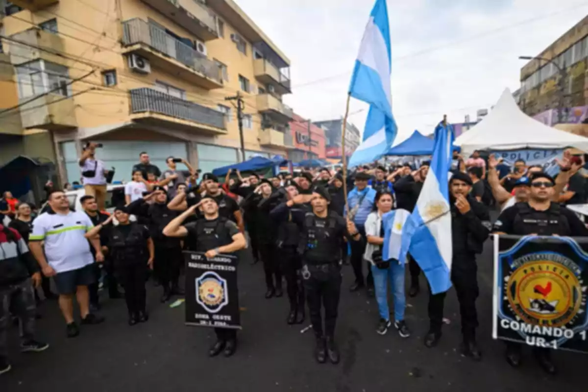 Un grupo de policías y civiles marchan por la calle portando banderas de Argentina y pancartas mientras algunos saludan de forma militar