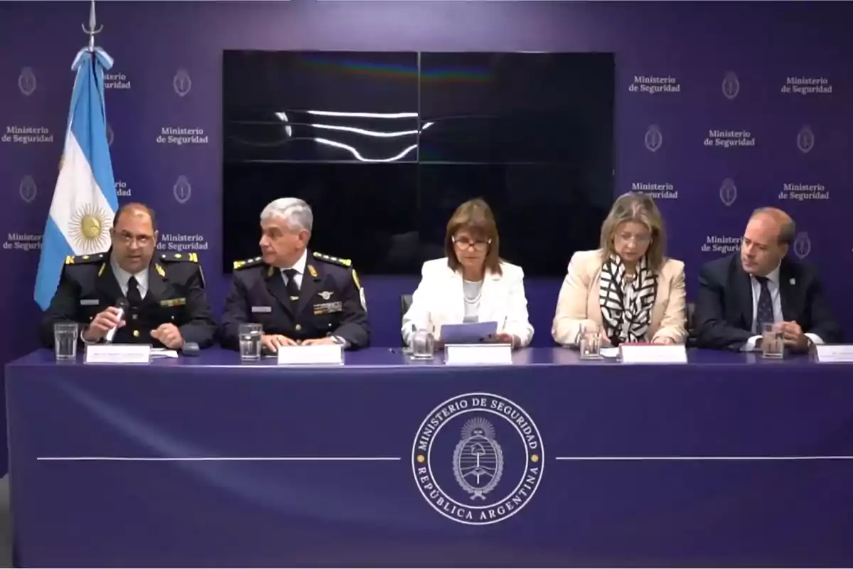 Cinco personas sentadas en una mesa durante una conferencia de prensa en el Ministerio de Seguridad de la República Argentina con una bandera argentina al fondo Cinco personas sentadas en una mesa durante una conferencia de prensa en el Ministerio de Seguridad de la República Argentina con una bandera argentina al fondo