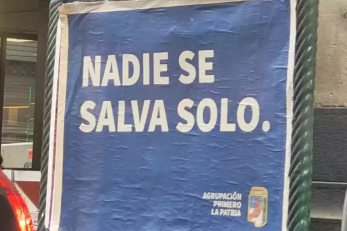 Blue sign with white letters that says "No one is saved alone," and in the bottom right corner appears the logo of a group called Primero la Patria.