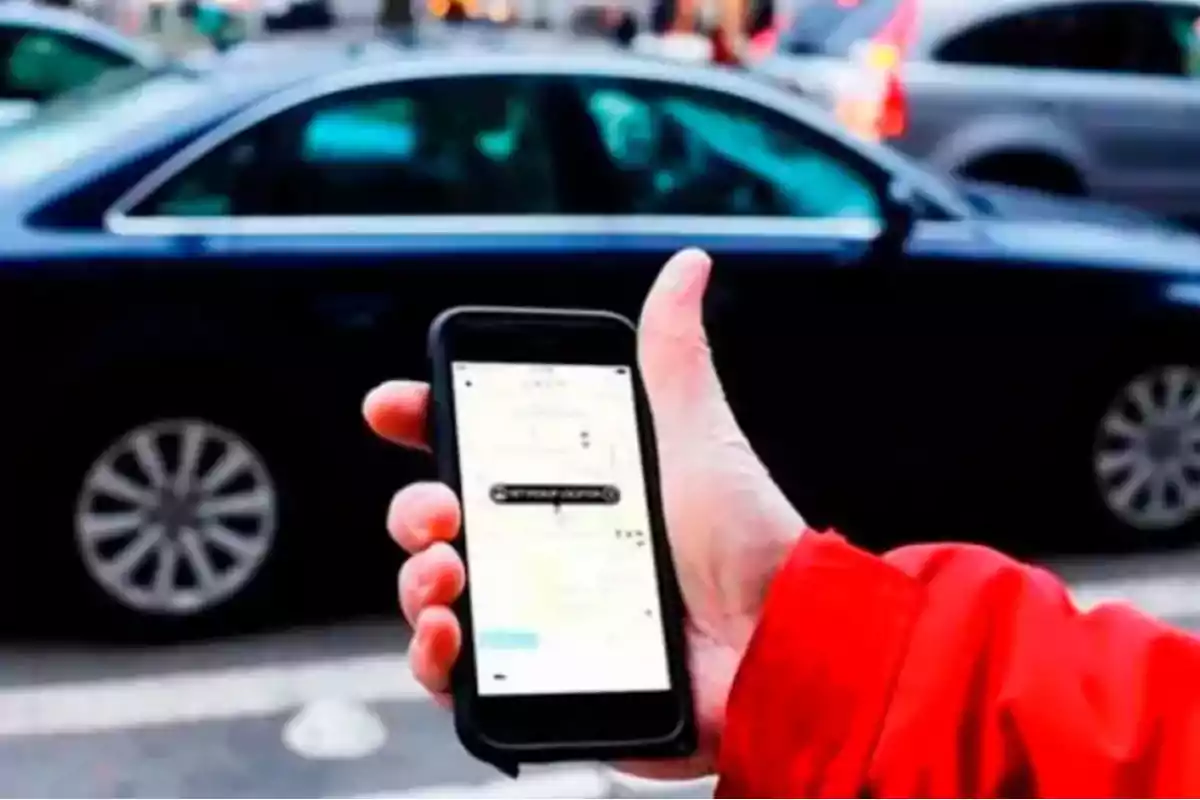 Person holding a mobile phone with a ride-hailing app open in front of a car on the street