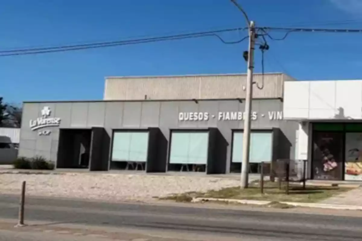 Facade of a store called La Varense Shop that sells cheeses, cold cuts, and wines in a modern building next to a paved street