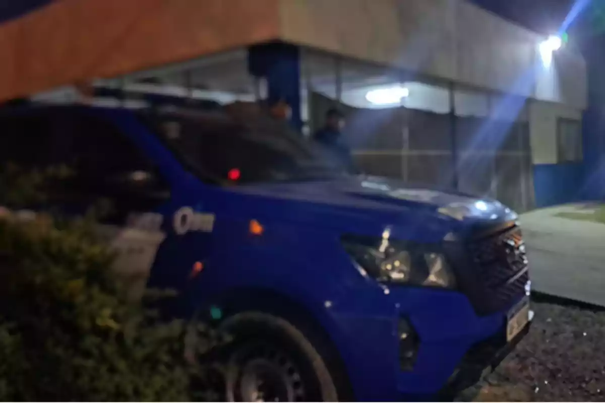 Blue pickup truck parked in front of a building lit up at night