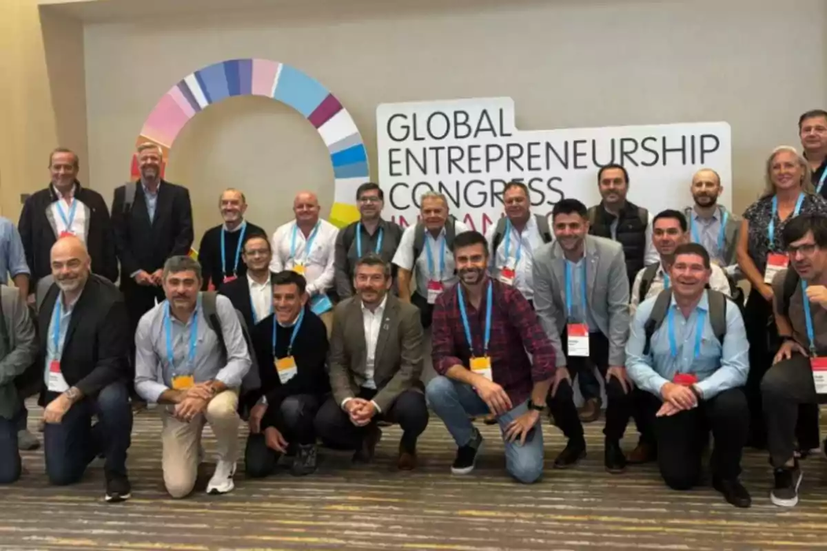 A group of people poses smiling in front of a sign that says Global Entrepreneurship Congress at a professional event.