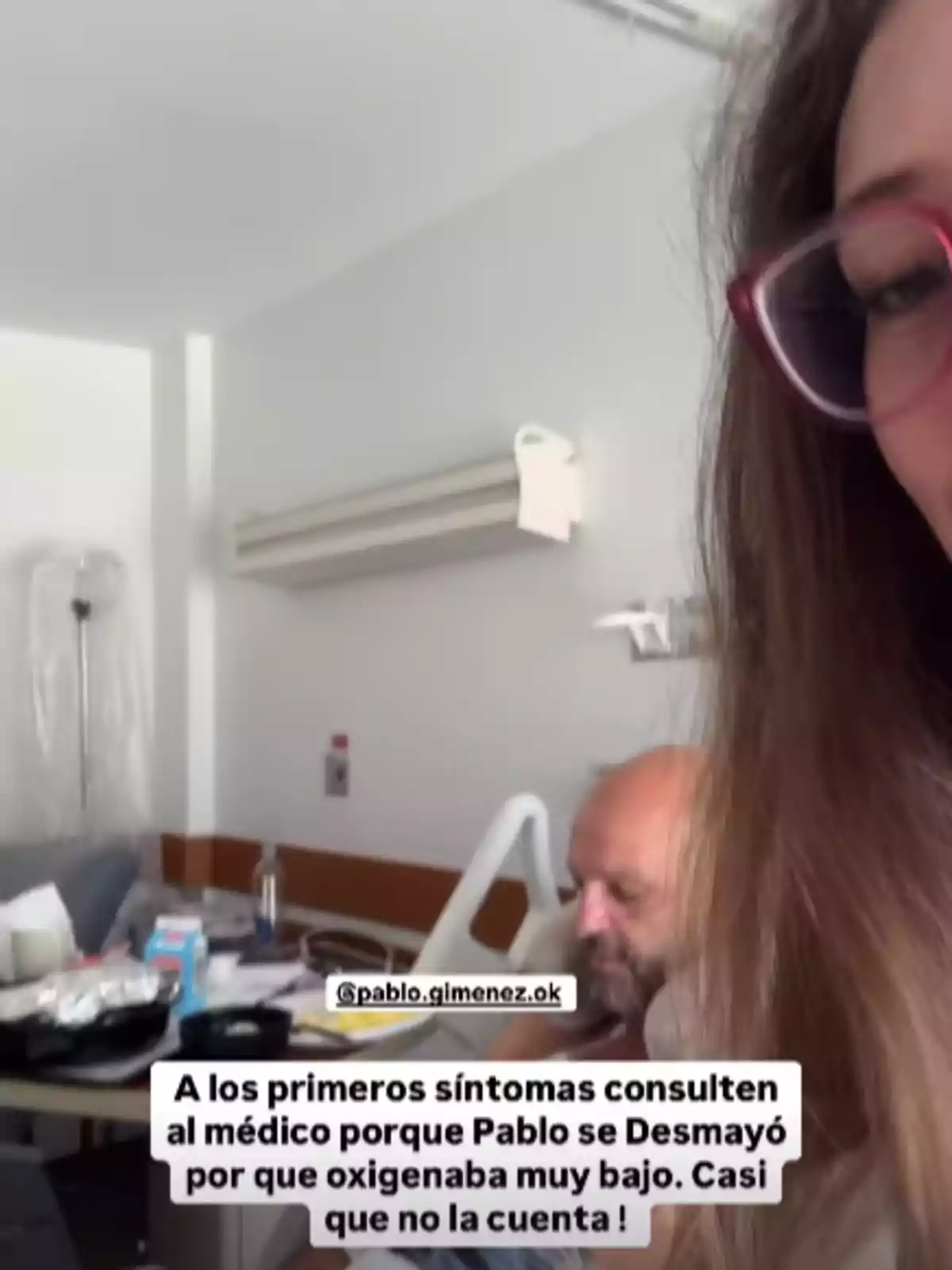 Una mujer con gafas rosadas aparece en primer plano mientras un hombre está sentado en una cama de hospital y en la imagen hay un mensaje advirtiendo sobre la importancia de consultar al médico ante los primeros síntomas Una mujer con gafas rosadas aparece en primer plano mientras un hombre está sentado en una cama de hospital y en la imagen hay un mensaje advirtiendo sobre la importancia de consultar al médico ante los primeros síntomas