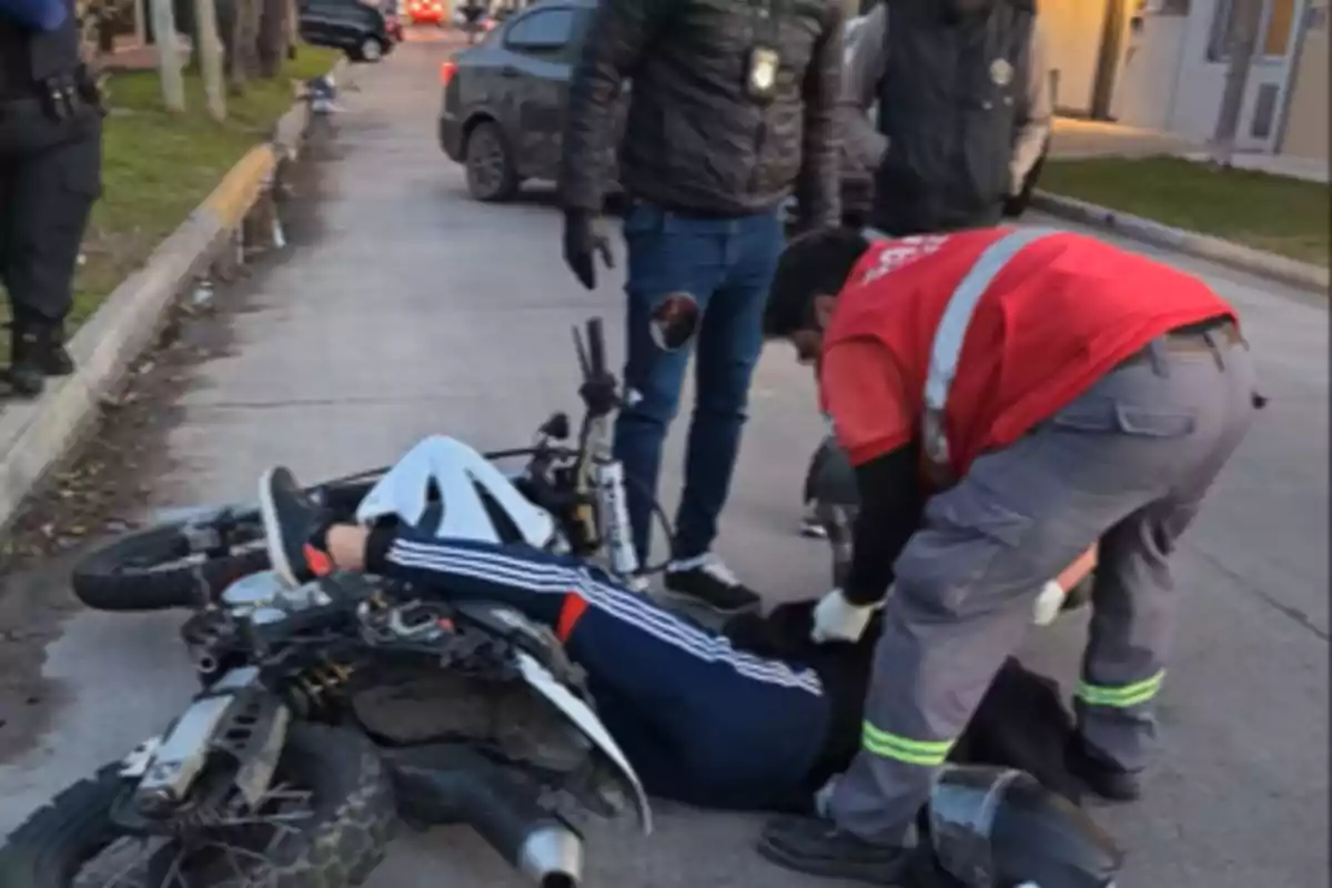 Paramedic assists an injured motorcyclist while others watch on the street.