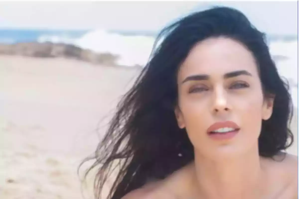 Dark-haired woman looking at the camera on a beach with sand and sea in the background Dark-haired woman looking at the camera on a beach with sand and sea in the background