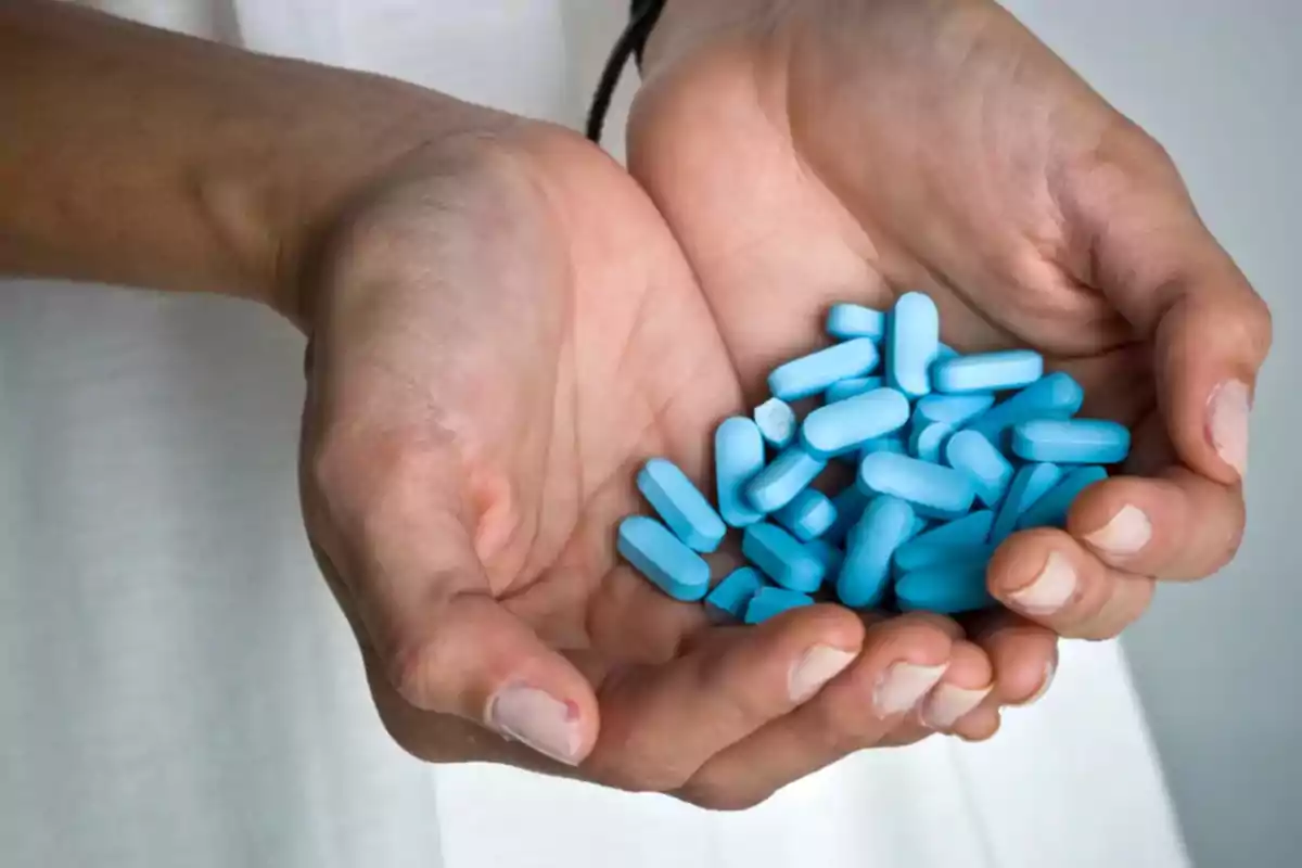 Manos sosteniendo varias pastillas azules