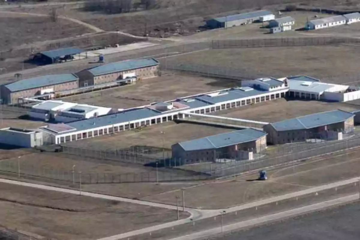 Vista aérea de un complejo penitenciario rodeado de varias cercas y edificios distribuidos en un terreno amplio y despejado Vista aérea de un complejo penitenciario rodeado de varias cercas y edificios distribuidos en un terreno amplio y despejado