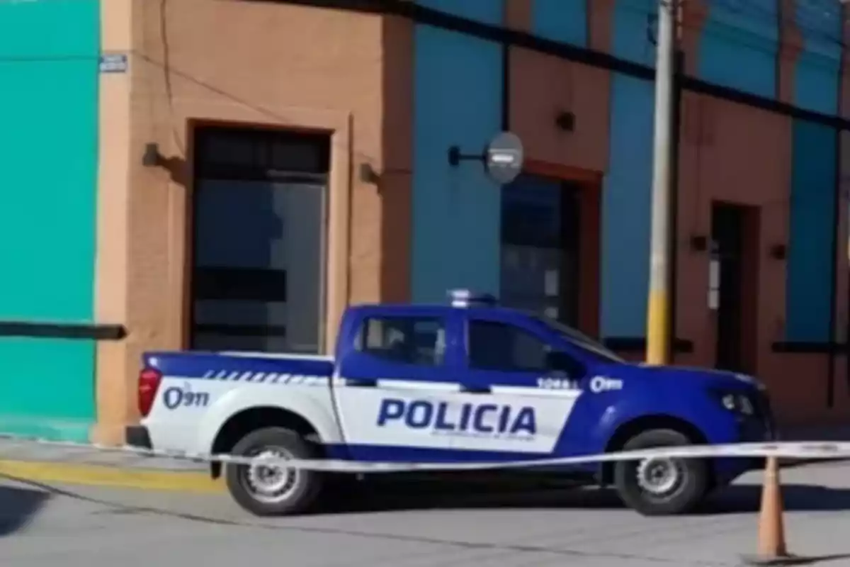 Patrulla de policía estacionada frente a un edificio con cinta de acordonamiento en la calle