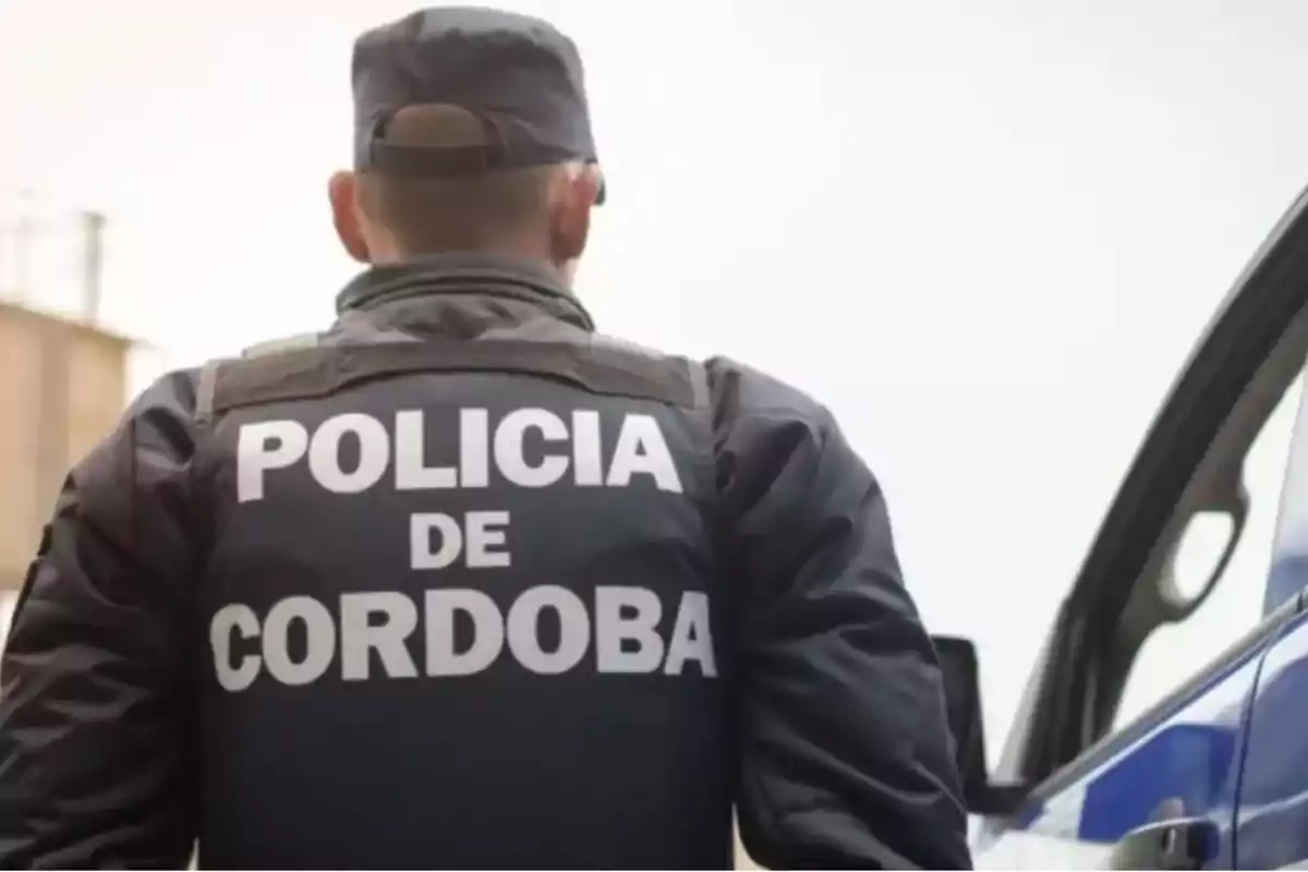 Un policía de Córdoba de espaldas junto a un vehículo patrulla Un policía de Córdoba de espaldas junto a un vehículo patrulla