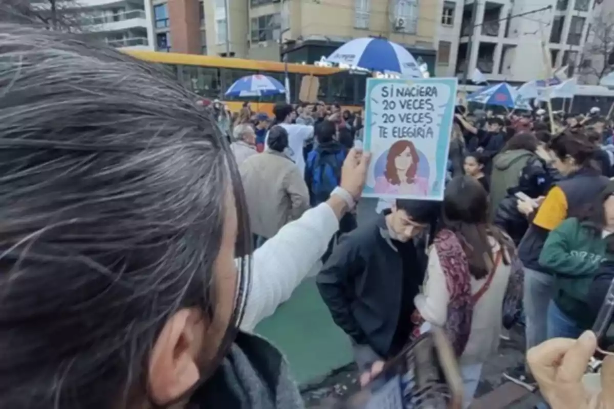 Persona sostiene un cartel con un dibujo de una mujer y un mensaje en una manifestación rodeada de gente en la calle Persona sostiene un cartel con un dibujo de una mujer y un mensaje en una manifestación rodeada de gente en la calle