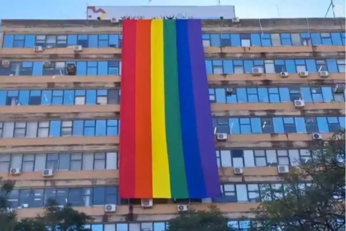 Edificio con una gran bandera arcoíris colgada en la fachada representando el orgullo LGBT Edificio con una gran bandera arcoíris colgada en la fachada representando el orgullo LGBT