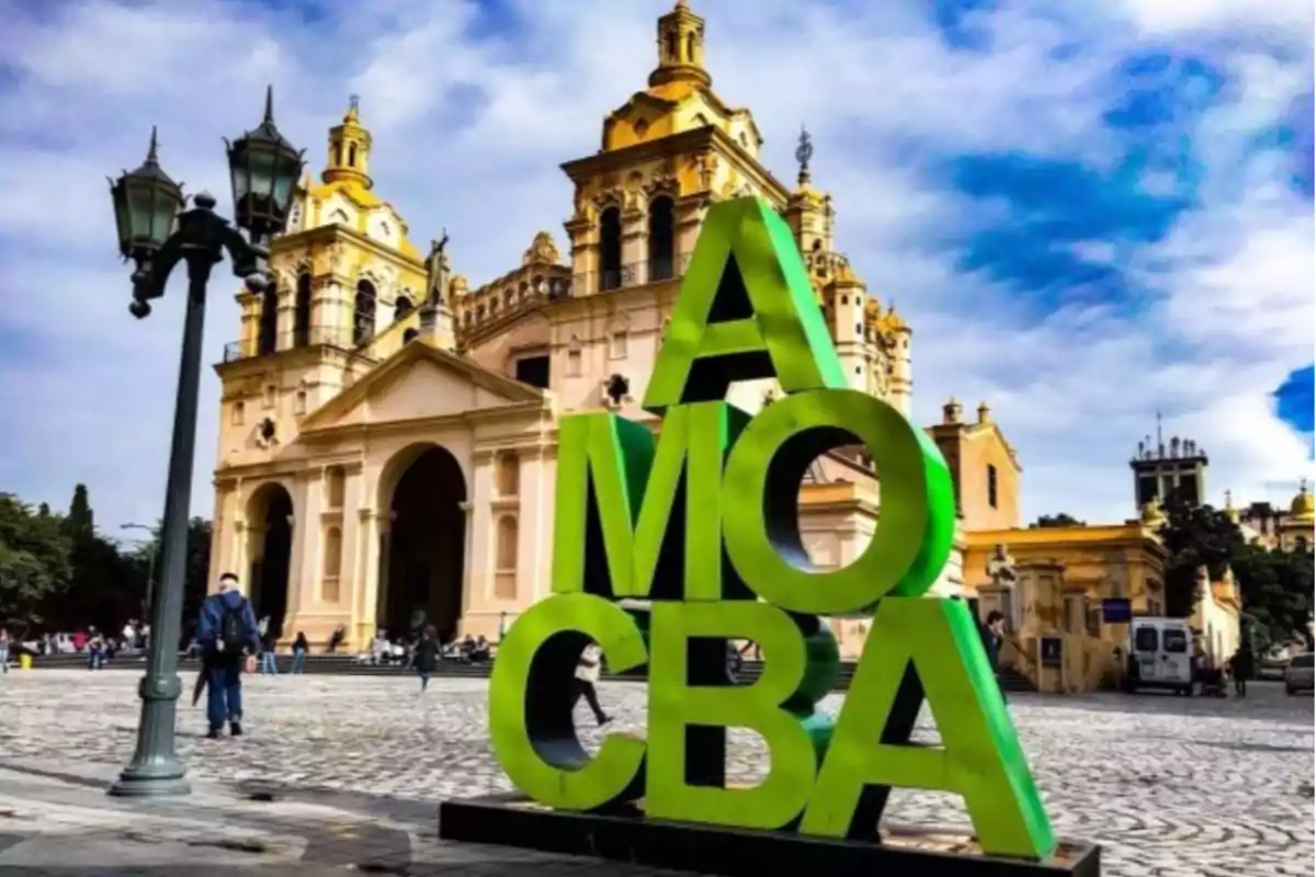 Escultura verde con las letras AMO CBA frente a la Catedral de Córdoba en una plaza con cielo parcialmente nublado. Escultura verde con las letras AMO CBA frente a la Catedral de Córdoba en una plaza con cielo parcialmente nublado.
