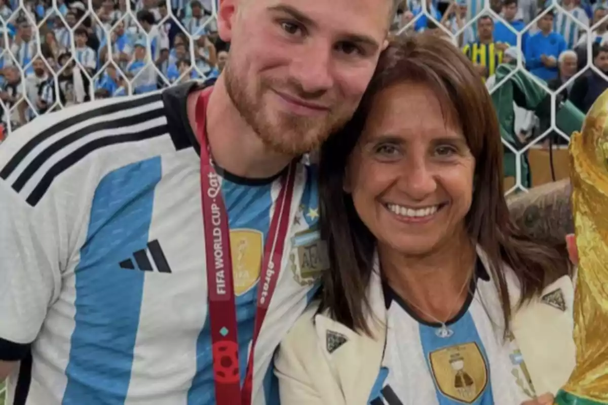 Un jugador de la selección argentina y una mujer sonríen juntos en el estadio mientras sostienen el trofeo de la Copa del Mundo Un jugador de la selección argentina y una mujer sonríen juntos en el estadio mientras sostienen el trofeo de la Copa del Mundo