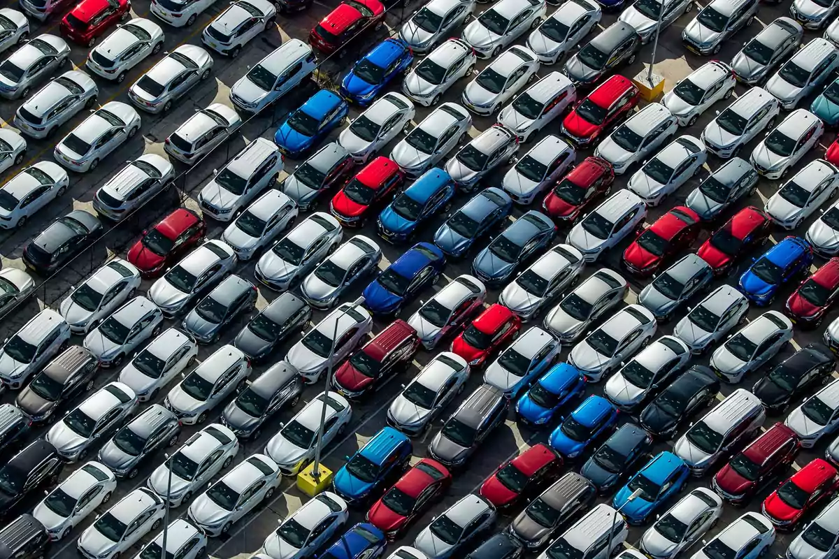 Aerial view of a parking lot filled with cars of different colors arranged in neat rows Aerial view of a parking lot filled with cars of different colors arranged in neat rows