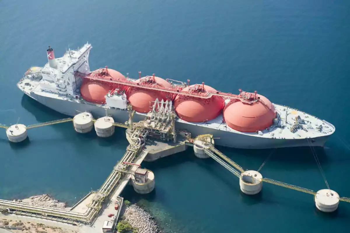 A liquefied natural gas cargo ship docked at a port with several storage spheres visible on its deck.