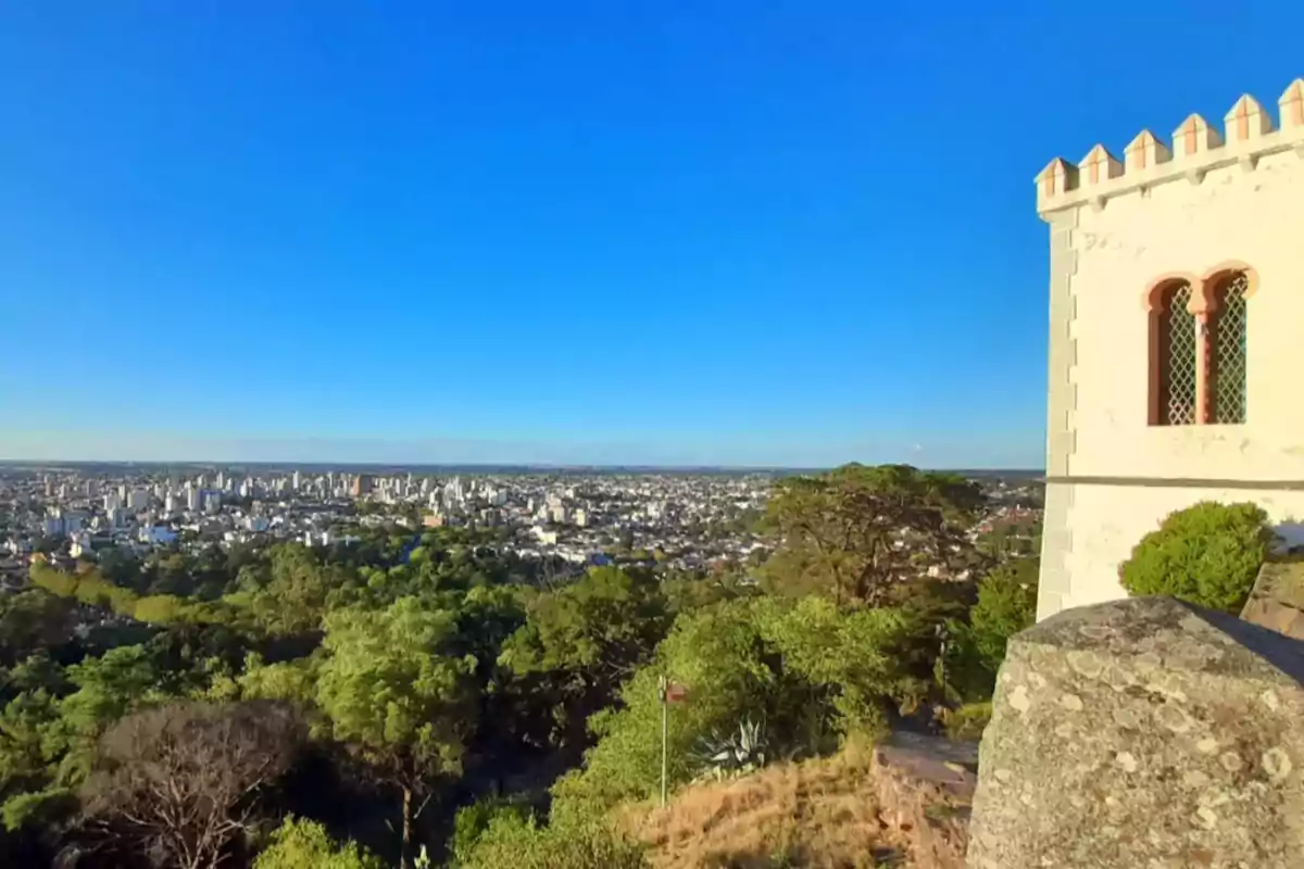 Vista panorámica de una ciudad con un edificio histórico en primer plano y un cielo despejado.