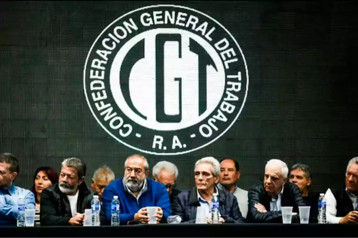 Several union leaders seated at a table in front of the logo of the General Confederation of Labor of the Argentine Republic