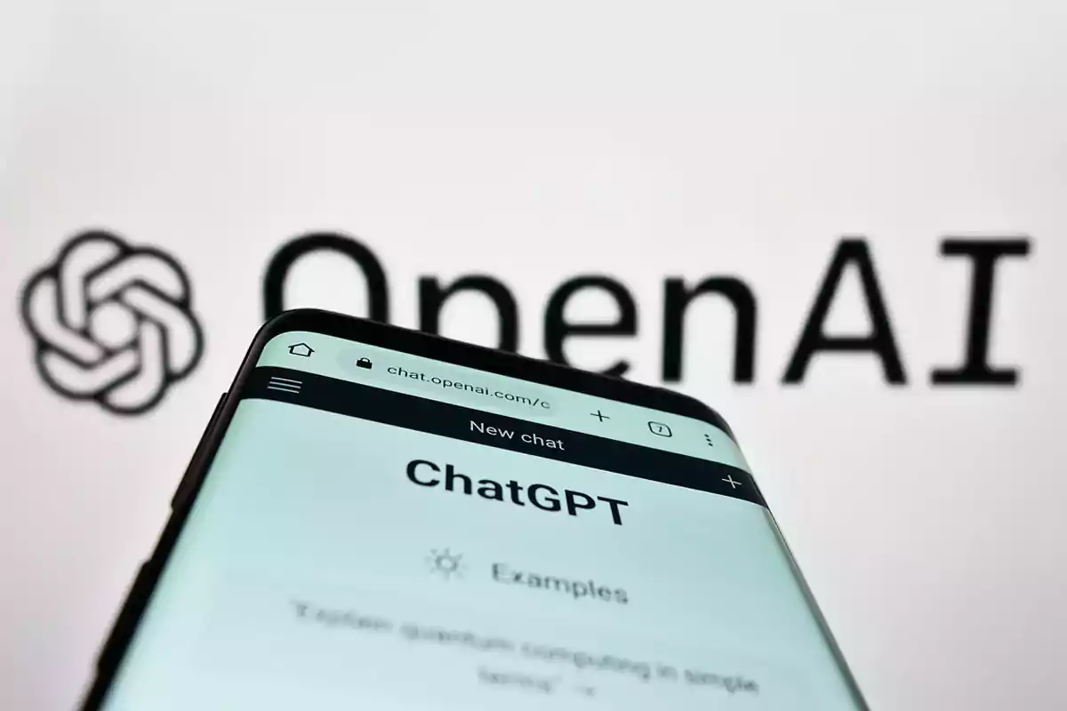 A mobile phone displays the ChatGPT page in the foreground, with the OpenAI logo and name blurred in the background. A mobile phone displays the ChatGPT page in the foreground, with the OpenAI logo and name blurred in the background.
