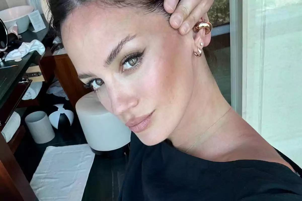 Mujer con cabello recogido y maquillaje natural tomando una selfie en un baño moderno Mujer con cabello recogido y maquillaje natural tomando una selfie en un baño moderno