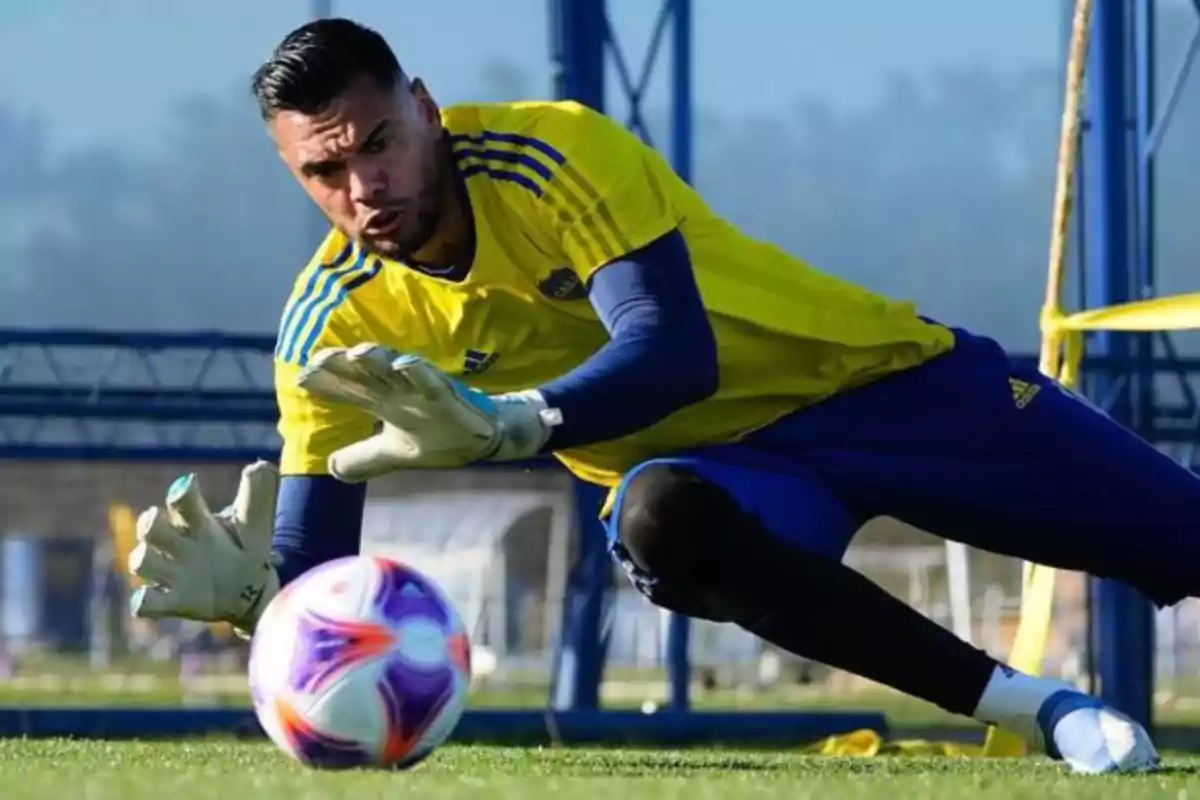 Un portero de fútbol con uniforme amarillo y azul se lanza para atrapar un balón durante un entrenamiento en un campo de fútbol. Un portero de fútbol con uniforme amarillo y azul se lanza para atrapar un balón durante un entrenamiento en un campo de fútbol.