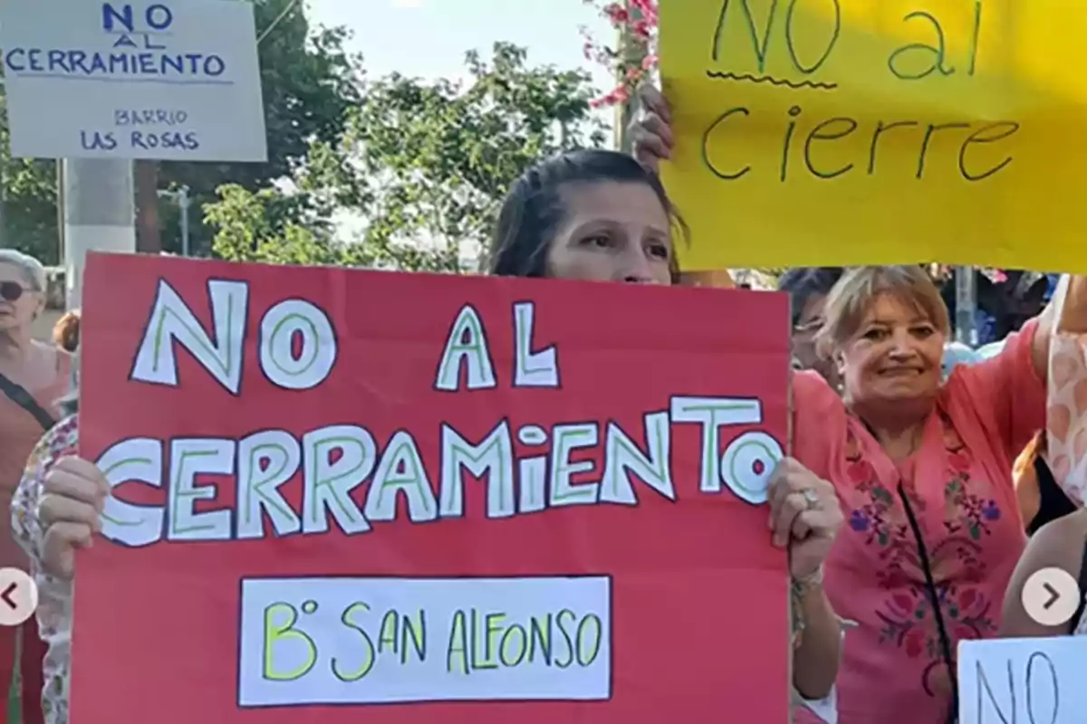 Personas manifestándose con carteles que dicen no al cerramiento y no al cierre en un espacio al aire libre Personas manifestándose con carteles que dicen no al cerramiento y no al cierre en un espacio al aire libre